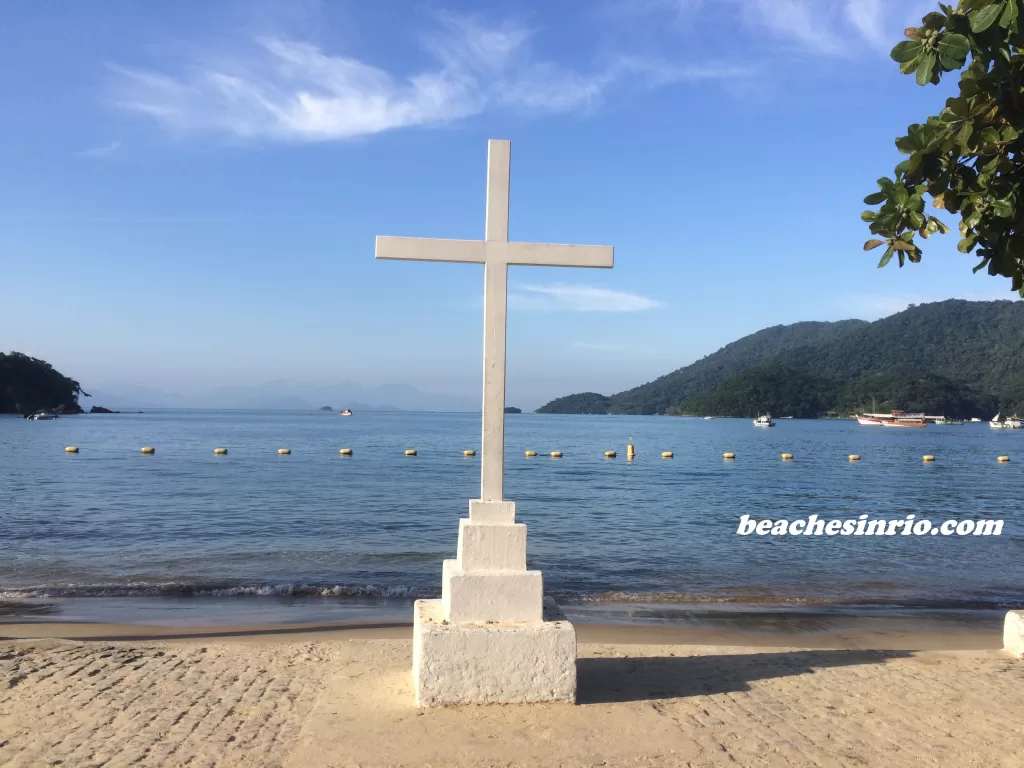 Wooden cross standing at the edge of Abraão Beach, Ilha Grande, symbolizing faith against a serene coastal backdrop