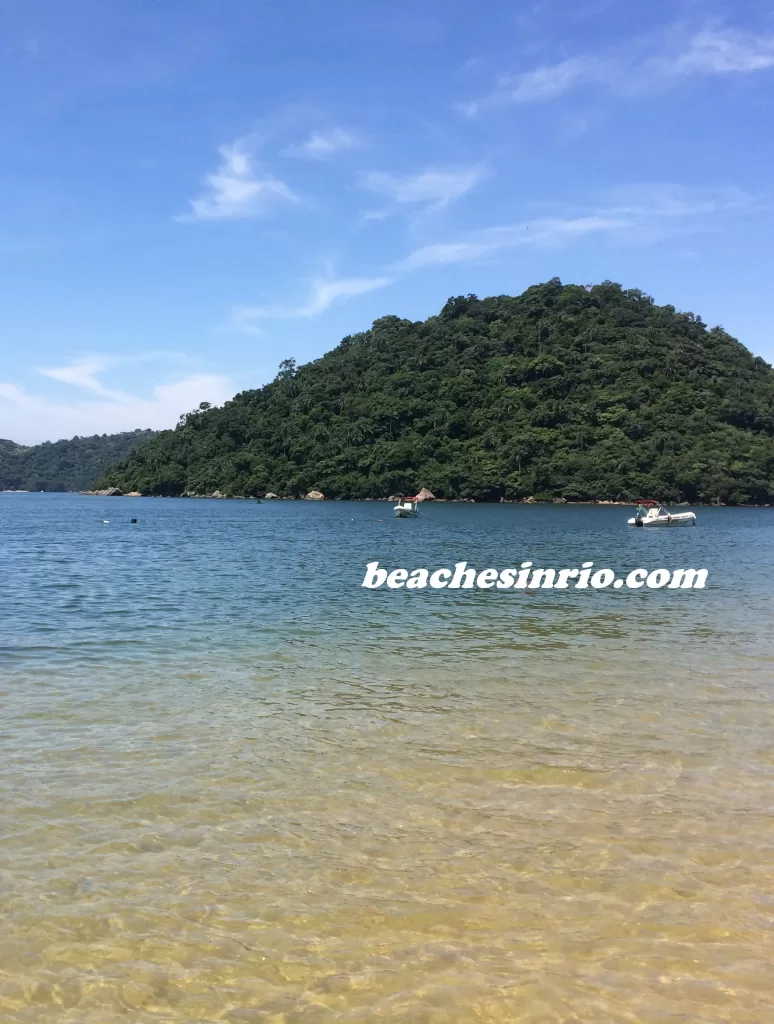 View of Junqueira Beach in Mangaratiba, Rio de Janeiro, with calm emerald-green waters, soft sand, and lush forested hills typical of Brazil’s Green Coast.