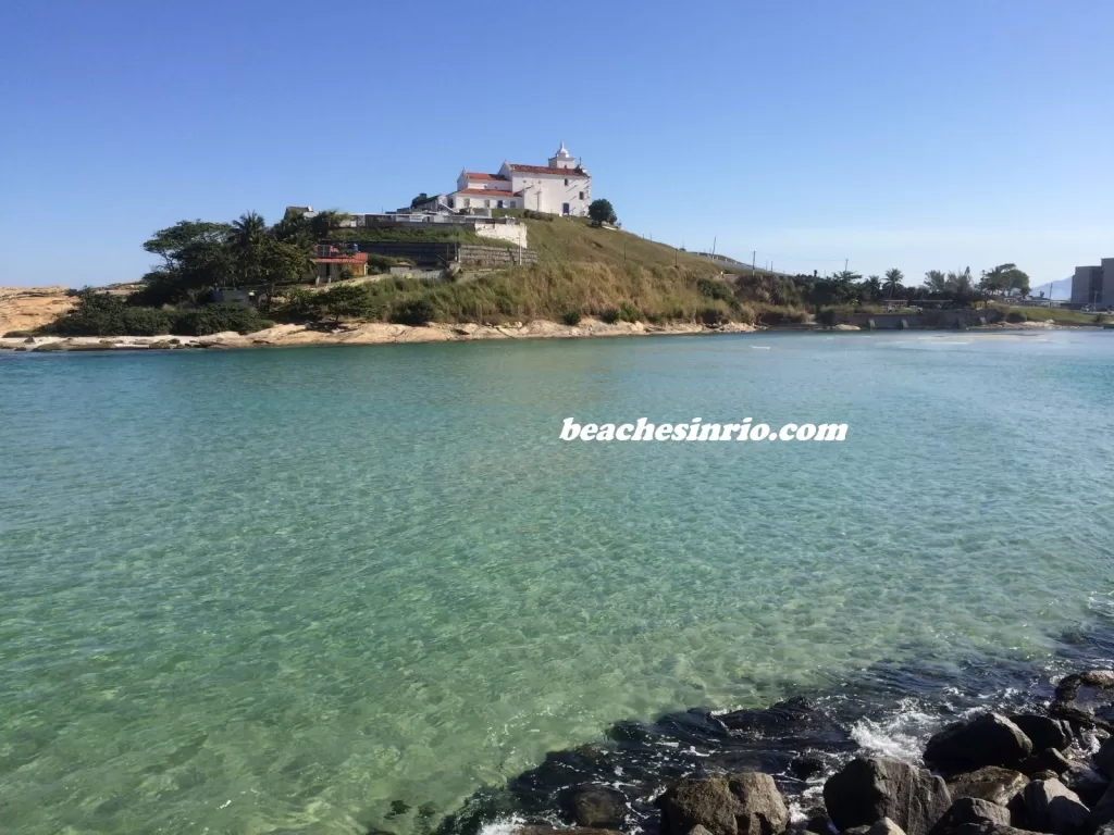 Scenic view of Lagoa de Saquarema at Praia da Barrinha, with calm waters and the Igreja de Nossa Senhora de Nazareth in the background.